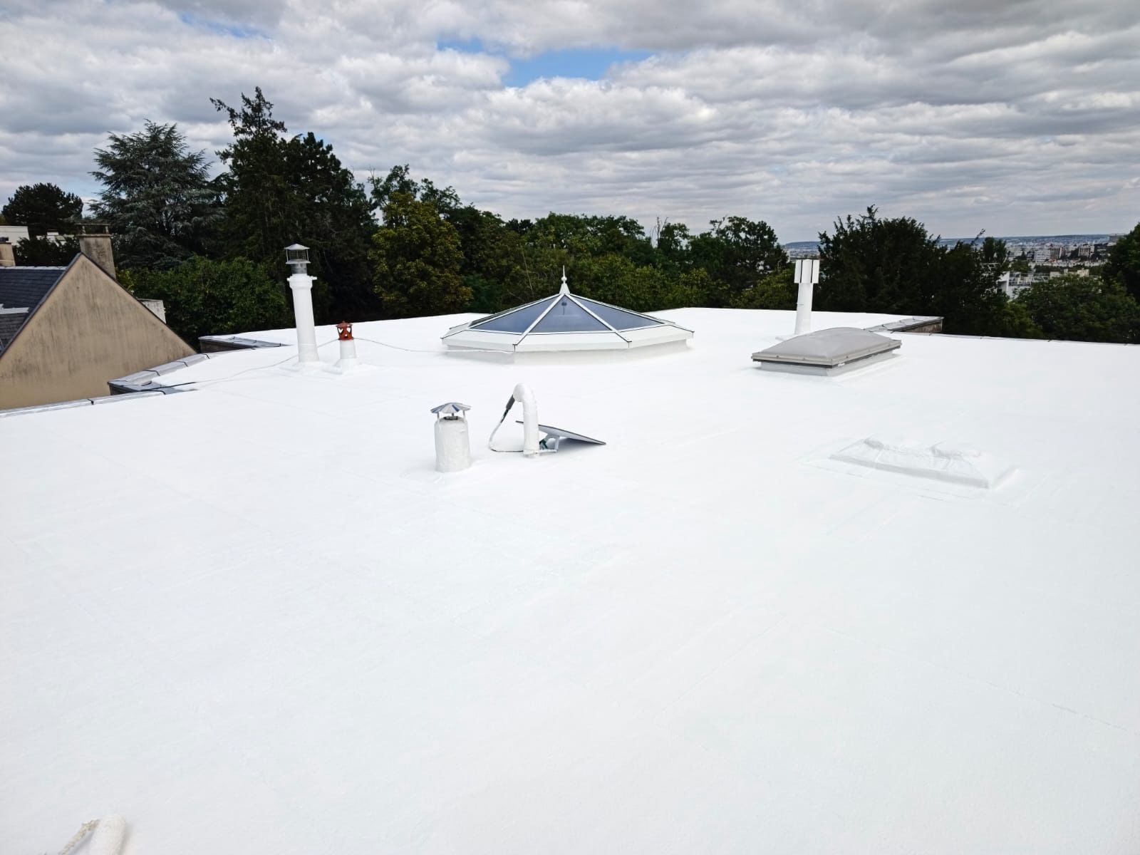 Application d’une peinture Cool Roof blanche sur une toiture-terrasse